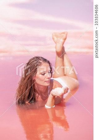 Woman in a pink salt lake. She lies in a white bathing suit. Wanderlust photo for memory 103834686