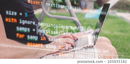 Man working on laptop in garden. Closeup of male hands typing on computer keyboard. 103835182