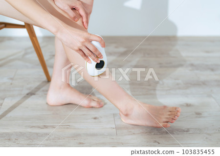 A woman using an epilator on her feet foot care self care 103835455