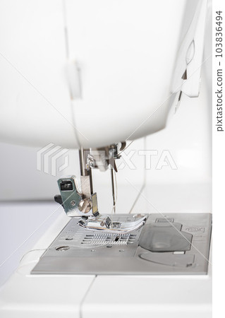 Modern white sewing machine presser foot closeup, macro Modern white sewing machine presser foot closeup, macro 103836494