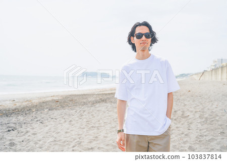 Man wearing sunglasses walking on the beach in summer Man wearing sunglasses walking on the beach in summer 103837814