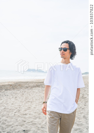Man wearing sunglasses walking on the beach in summer Man wearing sunglasses walking on the beach in summer 103837822