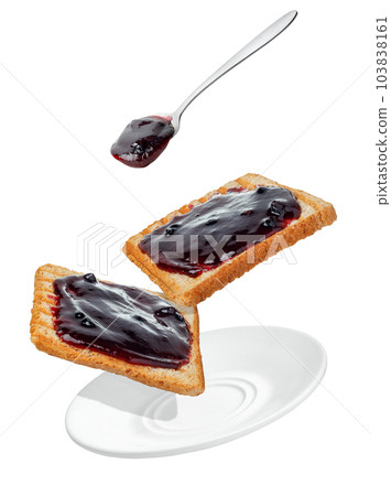 blueberry jam pouring from spoon on bread toasts in saucer isolated on white 103838161