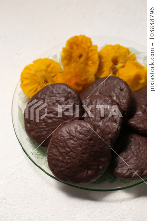 cookies in chocolate with cinnamon and candied pineapple, close-up 103838796