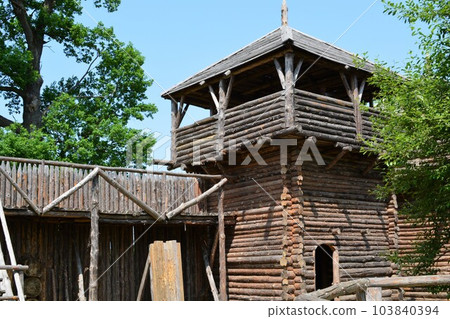 Ancient medieval wooden wall with a lookout wooden tower. 103840394
