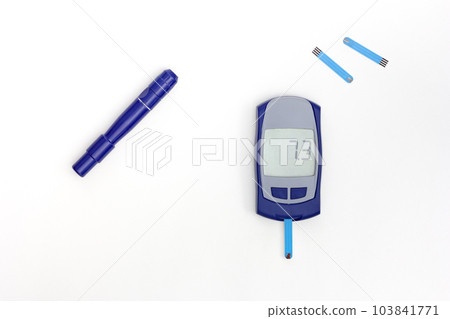 Top view of glucometer with 7.3 result on display with blooded test strip inside, lancet and test strips on white background 103841771