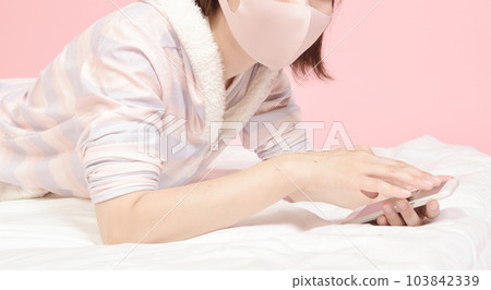 操作智能手機的穿著睡衣的女人 操作智能手機的穿著睡衣的女人 103842339