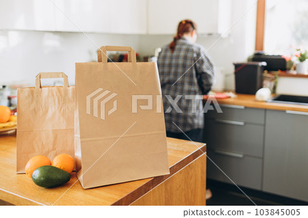 Two Food craft bags on the wooden table on sunny day. Delivery in any weather around the clock to the client. Fast food eco packaging with big breakfast or diner set with fruits 103845005
