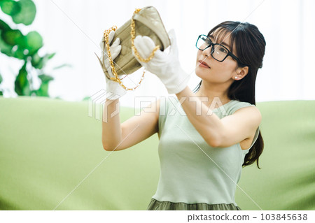 A woman using a flea market app to check products before selling unwanted items A woman using a flea market app to check products before selling unwanted items 103845638