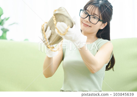 A woman using a flea market app to check products before selling unwanted items A woman using a flea market app to check products before selling unwanted items 103845639