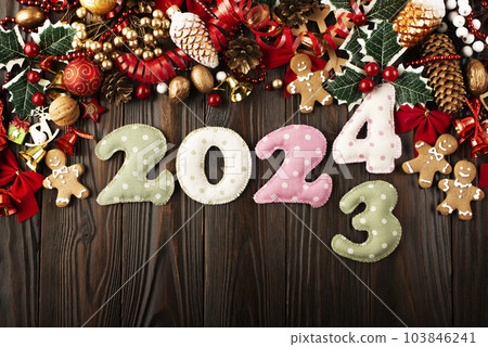 Colorful stitched digits 2024 of polkadot fabric with Christmas decorations flat lay background on wooden table Colorful stitched digits 2024 of polkadot fabric with Christmas decorations flat lay background on wooden table 103846241