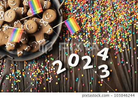 New year background of tray with gingerbread cookie men, rainbow flags and color sprinkles on wooden table New year background of tray with gingerbread cookie men, rainbow flags and color sprinkles on wooden table 103846244
