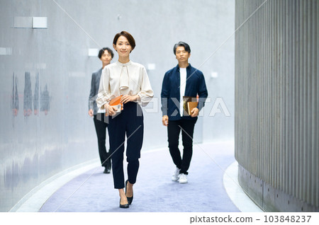 Career woman and male and female business team walking in the corridor Career woman and male and female business team walking in the corridor 103848237
