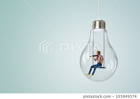 Man plays on violin sitting on light bulb Man plays on violin sitting on light bulb 103849374