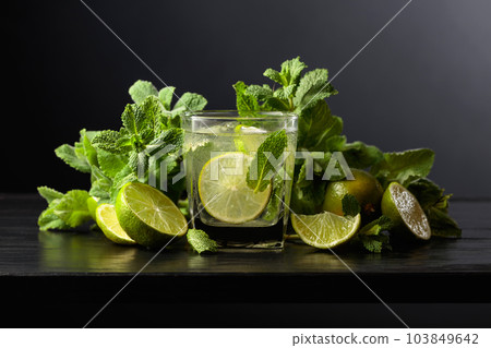 Mojito with ice, lime, and mint on a black background. Mojito with ice, lime, and mint on a black background. 103849642