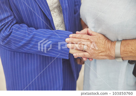 An elderly woman gently holds the hand of a young one. Close-up 103850760