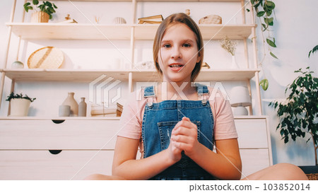 Child vlog. Digital conversation. Video conference. Confident casual girl talking gesticulating in light cozy modern interior room at home. 103852014