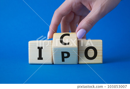 ICO and IPO symbol. Businessman hand turns wooden cubes with words ICO - initial coin offering and IPO - initial public offering. Beautiful blue background. Business concept. Copy space 103853007