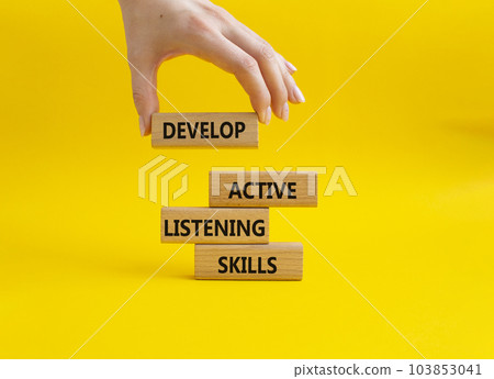 Listening skills symbol. Concept word Develop active listening skills on wooden blocks. Beautiful yellow background. Businessman hand. Business and Develop active listening skills concept. Copy space 103853041