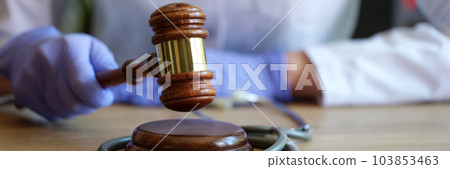 Woman doctor hands in gloves striking with judge gavel 103853463