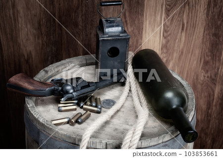 Old west revolver with cartridges and silver dollar and liquor bottle on barrel Old west revolver with cartridges and silver dollar and liquor bottle on barrel 103853661
