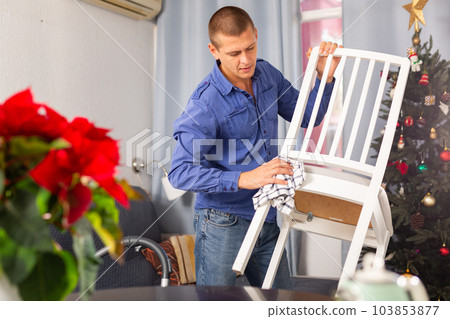 Man wiping dust from chair 103853877