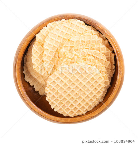 Cheese cracker in a wooden bowl. Snack in the shape of circular and wafer-thin slices, made of dough of wheat flour and cheese, baked crispy and golden brown, with a lattice pattern on the surface. 103854904