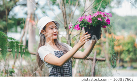 Young women doing hobbies taking care of plants, watering, shoveling flowers. In the garden during the break from work Young women doing hobbies taking care of plants, watering, shoveling flowers. In the garden during the break from work 103857602