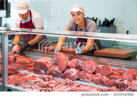 Butcher shop salesgirl giving V gesture while arranging meat display Butcher shop salesgirl giving V gesture while arranging meat display 103858460