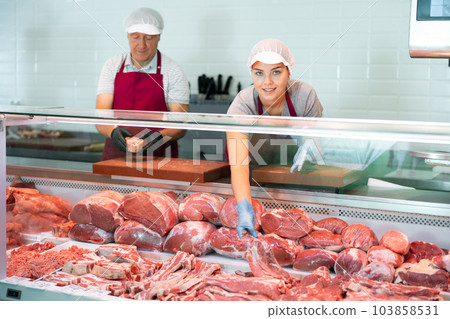 Young female butcher showing raw veal loin slices in butchery 103858531