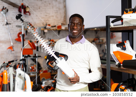 Man with electric shears in gardening tools store Man with electric shears in gardening tools store 103858552