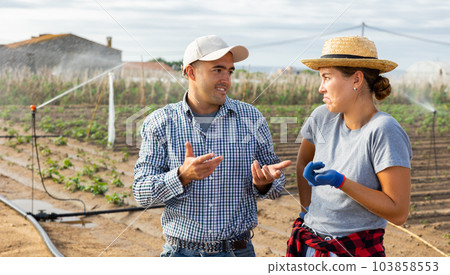 Cheerful man and woman gardeners talking on field Cheerful man and woman gardeners talking on field 103858553
