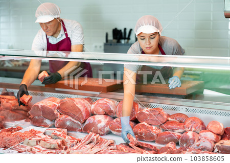 Interested young female owner of butcher shop offering raw veal 103858605