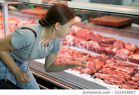 Female customer points with finger and orders beef brisket and sirloin 103858607