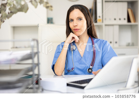 Woman doctor sitting at table in her office 103858776