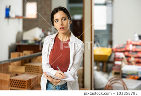 Female designer with papers working in apartment under renovation Female designer with papers working in apartment under renovation 103858795