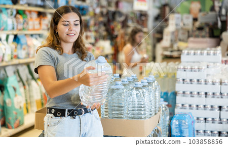 Girl buying bottle of water in grocery store 103858856
