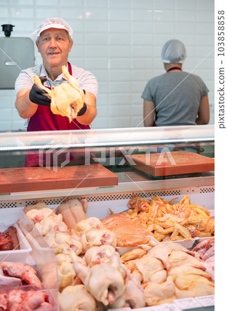 Adult man seller lays out chicken in butcher shop 103858858