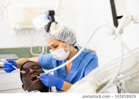 Dentist professional filling teeth for man patient sitting in chair 103858929