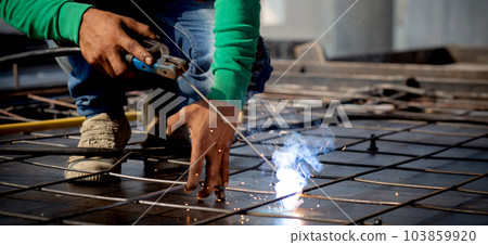 Closeup hands young worker using machine welding iron with hands working in industrial factory. 103859920