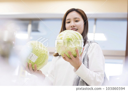 年輕女子在超市拿著白菜，選擇買哪一個 103860394