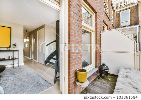 a living room with brick walls and white trim on the door, windows, and staircase leading up to the second floor 103861584
