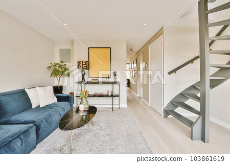 a living room with blue couches and stairs leading up to the second floor in this modern style condo apartment 103861619