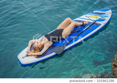 Young women Having Fun Stand Up Paddling in blue water seaamong the rocks in Montenegro. SUP Young women Having Fun Stand Up Paddling in blue water seaamong the rocks in Montenegro. SUP 103862286