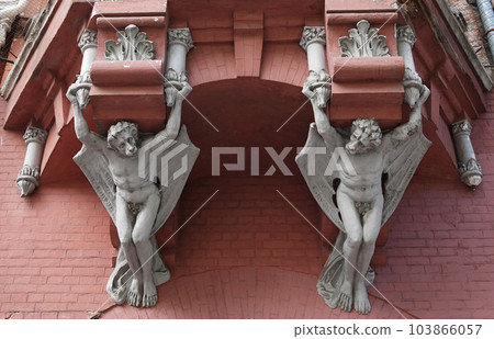 Kiev, Ukraine June 10, 2021: Sculpture of a Griffin head of a lion in a human body with bat wings on the facade of a building in the center of Kiev Kiev, Ukraine June 10, 2021: Sculpture of a Griffin head of a lion in a human body with bat wings on the facade of a building in the center of Kiev 103866057