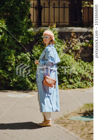 Woman in blue cloak and coral beret turned back 103866600