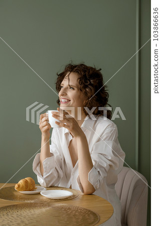 Young woman holding cup in her hands and smiling broadly 103866636