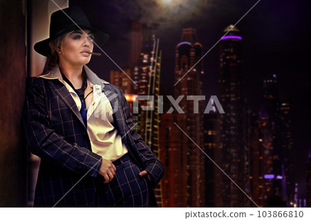 Woman in a suit with a cigarette against the background of the city at night Woman in a suit with a cigarette against the background of the city at night 103866810