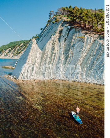 Traveller on stand up paddle board in sea with incredible landscape. Aerial drone view 103866871