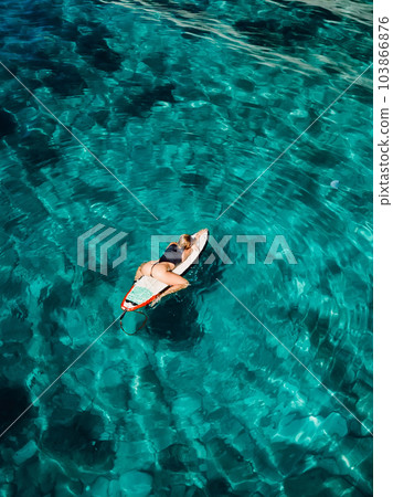 Surf girl on surfboard in tropical turquoise ocean. Aerial view of sexy surfer woman Surf girl on surfboard in tropical turquoise ocean. Aerial view of sexy surfer woman 103866876